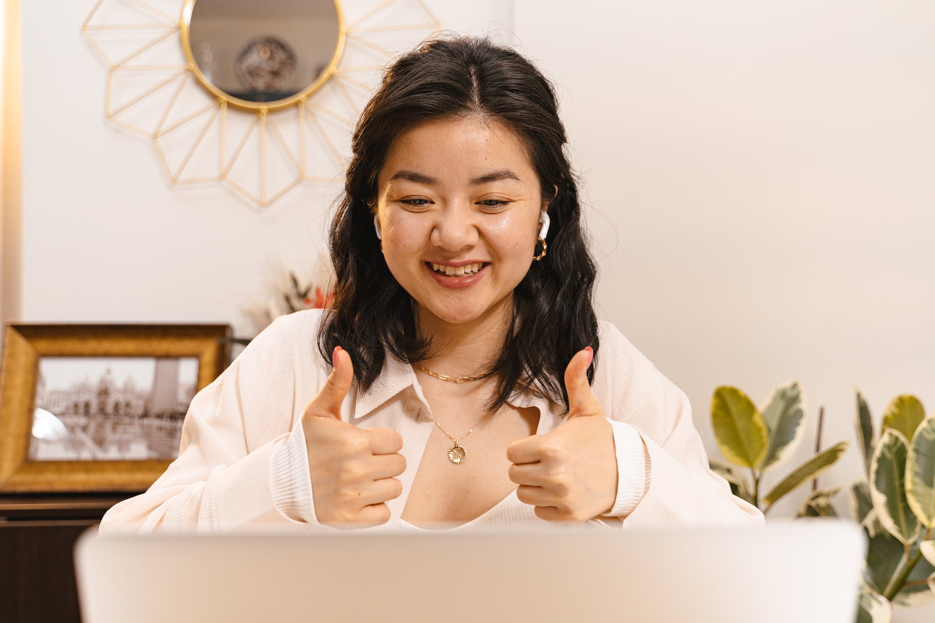 a woman in a video call doing a thumbs up